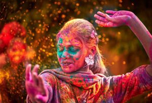 Portrait Of Young Indian Woman With Colored Face Dancing During Holi